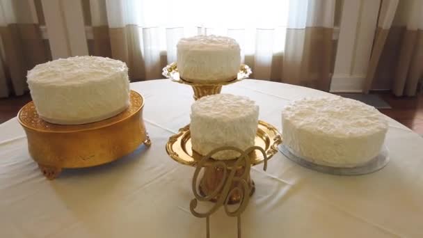 Čtyři svatební koláče stojí na kulatému stole s bílým ubrus — Stock video