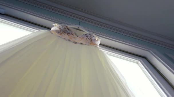 窓枠にぶら下がってエレガントなウェディングドレスのスローモーション明らかに バックレスデザイン ホワイトウェディングガウン パールアクセント — ストック動画