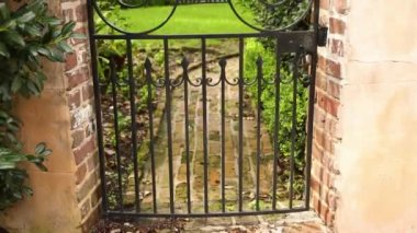 Güneşli bir günde eski bir evin arka planında taş bir duvarda metal bir kapı.