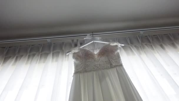 Revela en cámara lenta de elegante vestido de novia colgando en el marco de la ventana, diseño sin respaldo, vestido de novia blanco, detalles de perlas — Vídeos de Stock