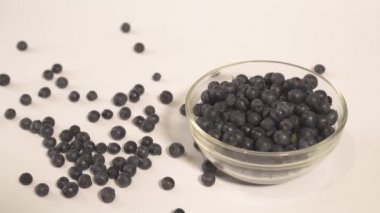 Erkek el çilek dolu bir tabak yakınında beyaz bir masadan yaban mersini alarak. Masada dağınık meyveler