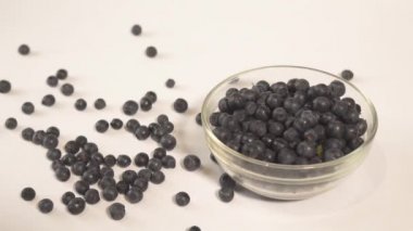 Erkek el çilek dolu bir tabak yakınında beyaz bir masadan yaban mersini alarak. Masada dağınık meyveler