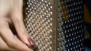 Bir kadının elinin yakın çekimi rendeleyiciye çikolata sürer. 4k