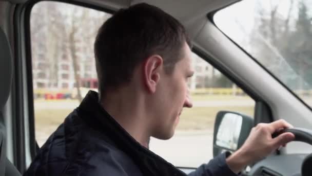 Młody Mężczyzna Rozmawia Pasażerem Jadąc Samochodem Ulicą Miejską Jedną Ręką — Wideo stockowe
