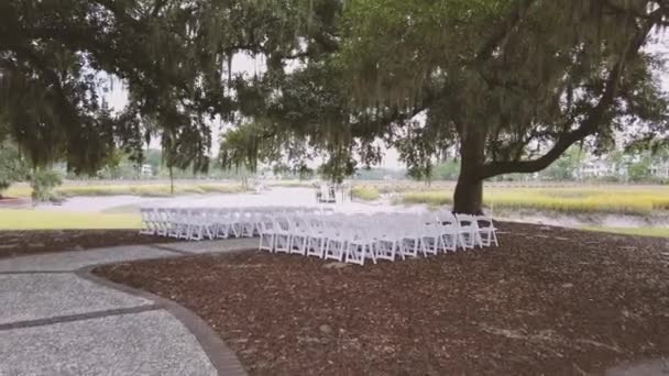 Uma cerimônia de casamento na margem do rio sob uma bela árvore grande. Decoração para uma cerimônia de casamento na margem do rio. Movimento lento 4k — Vídeo de Stock