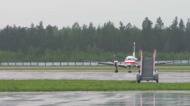 Beveiligingsauto met knipperlichten rijdt op de achtergrond. Vliegtuig geparkeerd op een luchthaven parkeerplaats. Motor, vleugels, patrijspoorten, cockpit, close-up. Vliegtuigen bij de startbaan klaar voor opstijgen 4K — Stockvideo