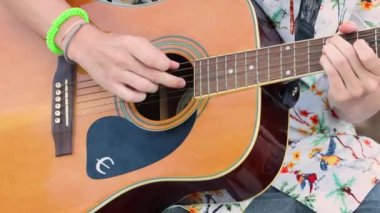 Akustik gitarla çalan müzisyen. Yakın çekim parmaklar, renkli bokeh. Rock, Blues, Jazz, pop müzik tarzı konserler, stüdyoda kayıt. Sanatçı hobisi, kendi melodilerini ve şarkılarını yarat 4k