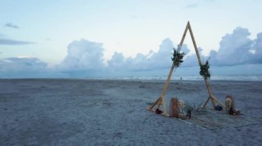 Deniz kıyısında düğün kemeri. Okyanus kıyısındaki sahilde yapılan bir gelenek. Palmiye ağaçları, kum ve gökyüzü. Adada düğün. Tropik açık hava düğün resepsiyonu. Düğün töreni için dekorasyon 4k