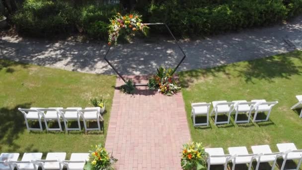 婚礼地点的顶部是一片绿地，以及靠近森林和大海的村庄里的一座房子。在草坪上装饰装饰的婚礼传统。美丽的花朵四千排白色椅子 — 图库视频影像