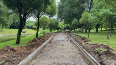 Nehrin yakınındaki eğlence parkında kaldırım tamiri, yeni asfalt. Kaldırıma beton bloklar döşemek. Güneşli bir günde yayalara giden bir yol. Açık havada çalışmak, sıkı çalışmak 4K