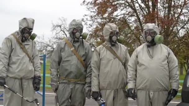 身着化学防护服的军事人员进行消毒 四名男子在隔离过滤防毒面具感染大楼 检疫的抗菌卫生措施 — 图库视频影像