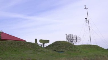 Askeri savaş radarı açık bulutlu gökyüzü boyalı. Radar yeşil ormana gizlenmiş. Hava araçlarını ya da gemileri tespit etmek için radyo dalgaları gönderiyor. Dar bir kiriş 4k ile hava sahasını tarar