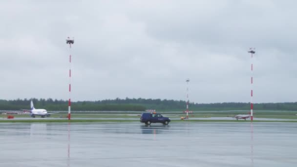 Αυτοκίνητο ασφαλείας με φώτα που αναβοσβήνουν οδηγεί στο παρασκήνιο. Αεροπλάνο σταθμευμένο σε πάρκινγκ αεροδρομίου. Μηχανή, φτερά, φινιστρίνια, πιλοτήριο, κοντινό πλάνο. Αεροσκάφος κοντά στο διάδρομο έτοιμο για απογείωση 4K — Αρχείο Βίντεο