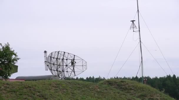 Militärisches Kampfradar in Armeefarbe mit wolkenlosem Himmel. Im grünen Wald getarntes Radar sendet Funkwellen aus, um Flugzeuge oder Schiffe zu erkennen. Dreht den Luftraum mit einem schmalen Strahl 4k fegen — Stockvideo