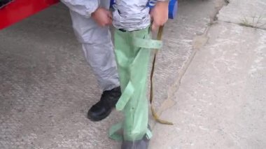 Koruyucu giysili bir adam özel lastik çizmeler giyiyor. Çevrenin radyasyon kirliliği. Adamın portresi. Salgın hastalık. Covid-19. Ekolojik Felaket. Temizlik kavramı