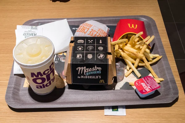 Mcdonald 's maestro burger sandwich, fritten, cheeseburger und tasse fanta zum trinken. — Stockfoto