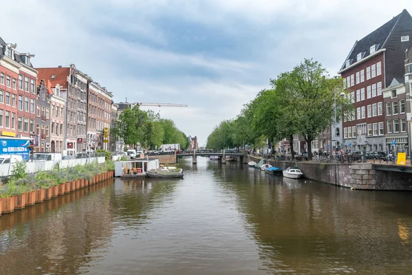 Pohled na amsterdamský kanál s malými bouky za oblačné denní. — Stock fotografie