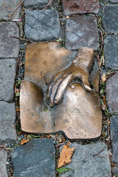 Escultura de mano sobre pecho en el Barrio Rojo de Ámsterdam. Relieve de bronce en los adoquines cerca del Oude Kerk. Creado e instalado por el artista Rob Hodgson . — Foto de Stock