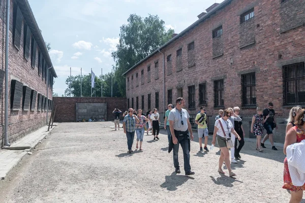 Menschen auf Hof mit Todesmauer zwischen Block 10 und 11 dienten als Hinrichtungsstätte für Masten, die nicht in Auschwitz standen. — Stockfoto