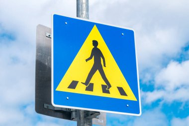 Bulutlu gökyüzünde yaya yol işareti.