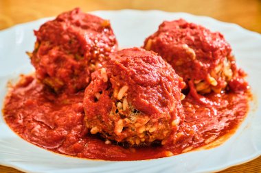 Beyaz tabakta domates soslu pilav ile köfte.