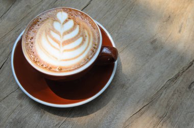 Kahverengi kahve fincanında kapuçino. Tahta bir masaya yerleştirilmiş.