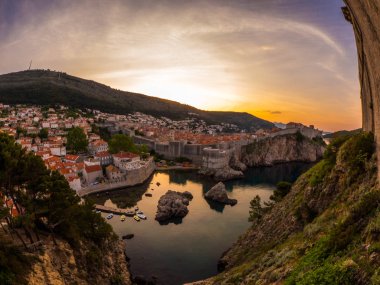 Muhteşem geniş açı görüntülemek tarihi kent mesafe ve Adriyatik Denizi aşağıdaki tepelerde taş duvarlarla çevrili Dubrovnik Hırvatistan üzerinden bakan sarı ve turuncu bir gündoğumu.