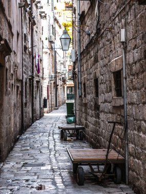 Caddede bir dar taş döşeli duvar ev ve kapı ve iki ahşap teslim vagonlar veya Dubrovnik Hırvatistan Eski kentte arabaları ile seyir görünümü.