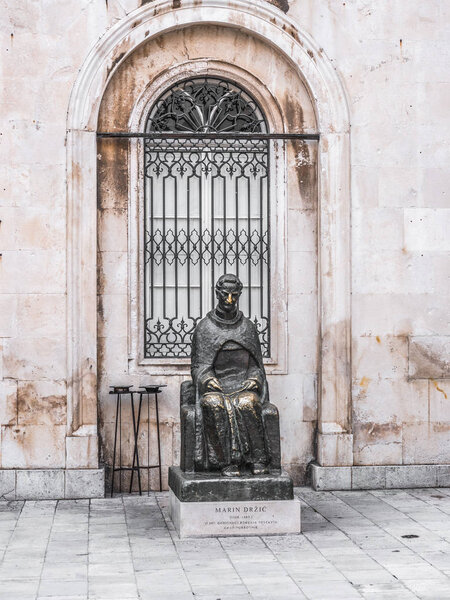 Photograph of the famous good luck bronze sculpture of Marin Drzic a Croatian poet and playwright with nose polished yellow from people rubbing the statues nose in old town in Dubrovnik Croatia.