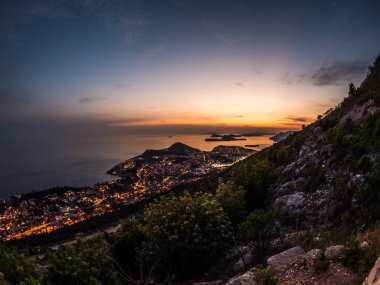 Güzel günbatımı fotoğraf güneş dips ada ve kıyı şeridi şehir Dubrovnik aşağıda olarak görülen yukarıdan Srd tepe üzerinde de dahil olmak üzere Hırvatistan ufukta aşağıda olarak alacakaranlıkta.