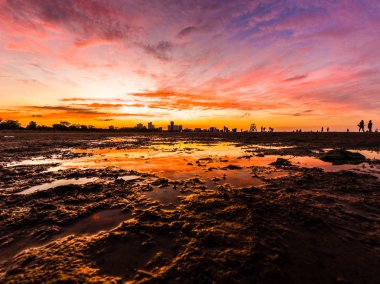 Güzel, parlak, doymuş ve canlı günbatımı turuncu, sarı, mavi, pembe ve mor renkli bulutlar yağmur su birikintileri Chicago Illinois Montrose plajda kuma yansıtan yukarıda gökyüzünde ile.