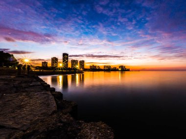 Çok güzel uzun pozlama günbatımı fotoğrafı Foster Plajı'nda Michigan Gölü arasında highrise binalar ve renkli mavi mor ve turuncu renkli gökyüzü ufukta arıyorsunuz.