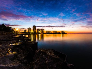 Çok güzel uzun pozlama günbatımı fotoğrafı Foster Plajı'nda Michigan Gölü arasında highrise binalar ve renkli mavi mor ve turuncu renkli gökyüzü ufukta arıyorsunuz.