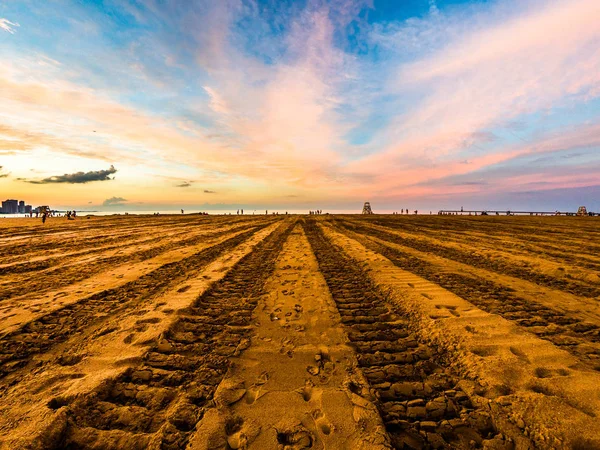 Buldozer parça ve Montrose Beach Chicago Michigan Gölü doğru günbatımında bulutlar ve gökyüzü yukarıdaki güzel renkleri ile önde gelen kumdaki.