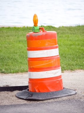 Chicago'nun lakefront su ötesinde ve çim üzerinde bir asfalt bisiklet yolu yakınındaki bir tek turuncu inşaat varil fotoğrafı.
