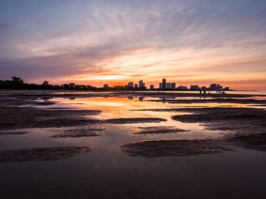 Güzel, parlak, doymuş ve canlı günbatımı turuncu, sarı, mavi ve mor renkli bulutlar yağmur su birikintileri Chicago Illinois Montrose plajda kuma yansıtan yukarıda gökyüzünde ile.