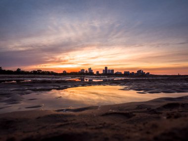 Güzel, parlak, doymuş ve canlı günbatımı turuncu, sarı, mavi ve mor renkli bulutlar yağmur su birikintileri Chicago Illinois Montrose plajda kuma yansıtan yukarıda gökyüzünde ile.