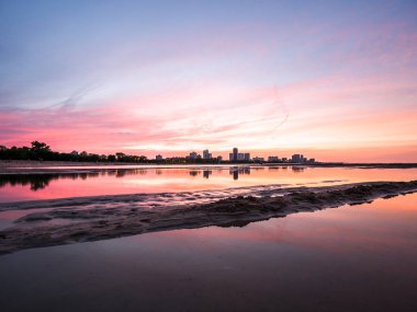 Güzel, parlak, doymuş ve canlı günbatımı turuncu, pembe, mavi ve mor renkli bulutlar yağmur su birikintileri Chicago Illinois Montrose plajda kuma yansıtan yukarıda gökyüzünde ile.