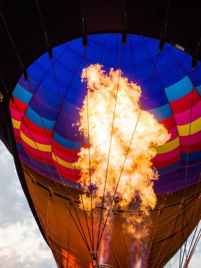 Fotoğraf bir sıcak hava balonu içinde seyir yakından bir ateş topu ya da alevler yukarı doğru dramatik bulutlar ile renkli balon içine gün batımında çekim ötesinde Galena Illinois.