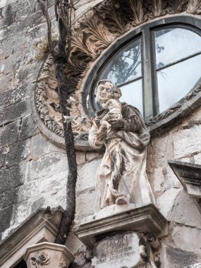 Old Town Dubrovnik Hırvatistan, kalbinde yerel ustalar, alınlıklı küçük adak kiliseyi yukarıda bir pod dışında büyüyen bir selvi ağacı ile St Joseph heykelinin portre görünümü.