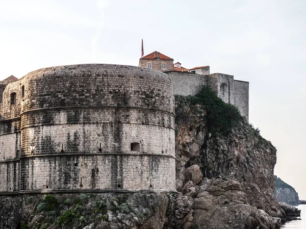 Tarihi Duvar görünümünü surlar Adriyatik Denizi üzerinde sarp bir kayalık uçurum güneşli bir günde Dubrovnik, Hırvatistan'da oturan yuvarlak köşe yapısı ile takviye edilmiş.