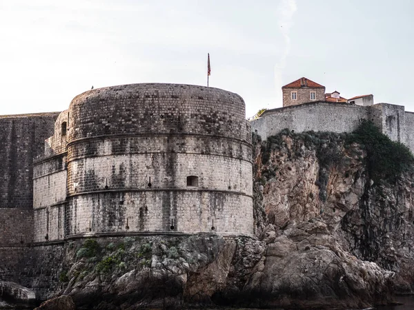 Tarihi Duvar görünümünü surlar Adriyatik Denizi üzerinde sarp bir kayalık uçurum güneşli bir günde Dubrovnik, Hırvatistan'da oturan yuvarlak köşe yapısı ile takviye edilmiş.