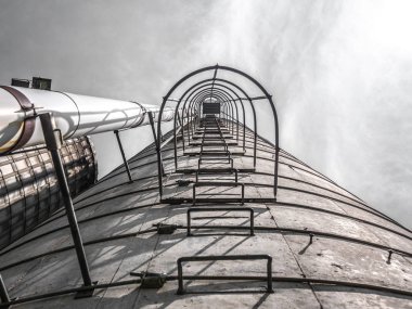 Güzel dramatik tarım fotoğraf beton inanmayarak seyir silo metal merdiven ve gri bulutlu gökyüzü yukarıdaki ile kafes.