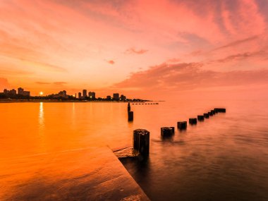Güzel turuncu renkli Günbatımı Fotoğraf beton bir satır aşağı seyir Michigan Gölü su üzerinde sakin su yansıtan çelik kazık dolu.
