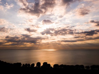 Muhteşem panoramik gündoğumu görünümü aşağı Michigan Gölü su altında ve ağaç kıyı ön planda yansıtan yukarıda renkli turuncu ve mavi bulutlu gökyüzü ile parlak ışınları ile.