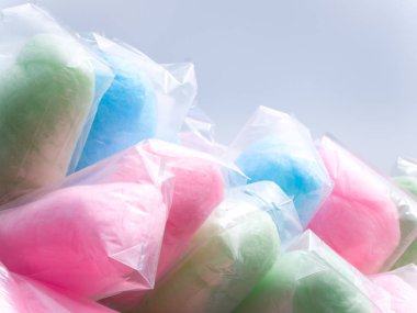Renkli çanta dahil olmak üzere yeşil, pembe, mavi ve mor bir sokak satıcısı sopa ile gri gökyüzü bir olay sırasında pamuk şeker dolu.