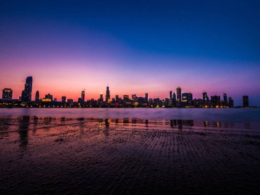 Çok güzel uzun pozlama Chicago manzarası fotoğraf gökyüzü ve ışıkları açın highrise bina olarak su ve ıslak kaldırımda yansıtan pembe, mor ve mavi renkleri ile güneş battıktan sonra sadece.