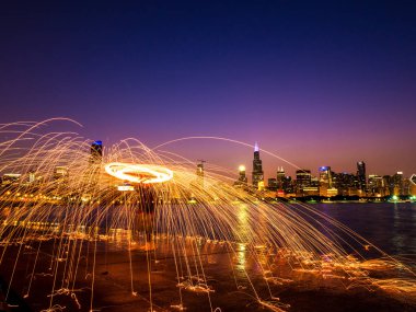 Güzel bir çelik yün kıvılcım spinner Michigan Gölü boyunca su yansıtan Chicago şehir manzarası ve highrise binalar gece görünümünü üzerinde pembe ve mor gökyüzü ile fotoğrafı.