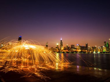 Güzel bir çelik yün kıvılcım spinner Michigan Gölü boyunca su yansıtan Chicago şehir manzarası ve highrise binalar gece görünümünü üzerinde pembe ve mor gökyüzü ile fotoğrafı.