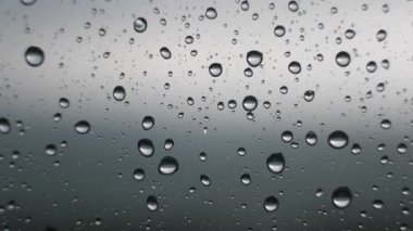 Rüzgarda oynatmak gibi bir şeffaf cam pencere bölmesinde damlacıkları odaklı bir bulutlu, kasvetli, bulutlu, yağmurlu hava gün toplama aşırı makro video closeup yağmur damla.